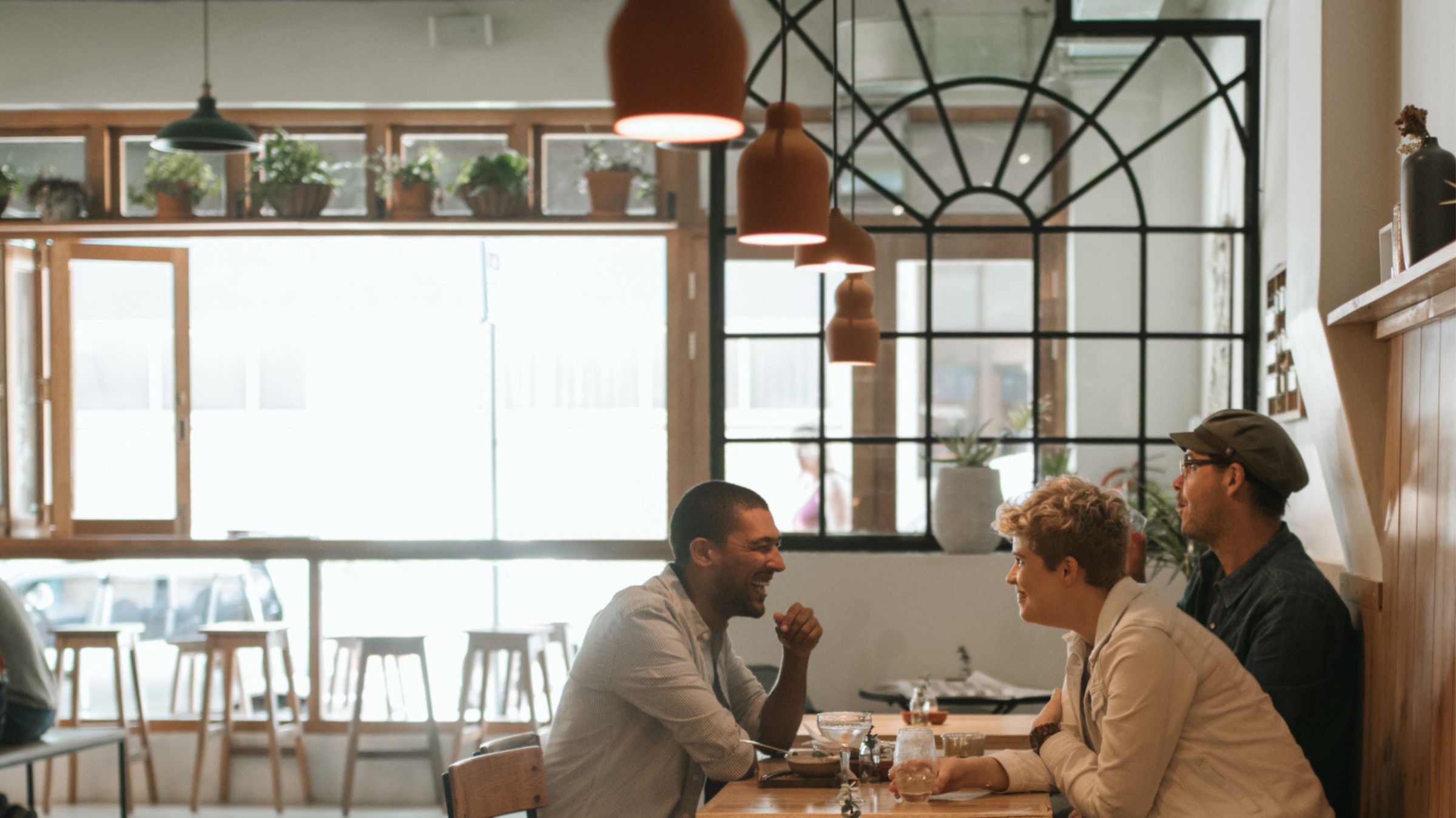 Friends talking and laughing together at a bright cafe table