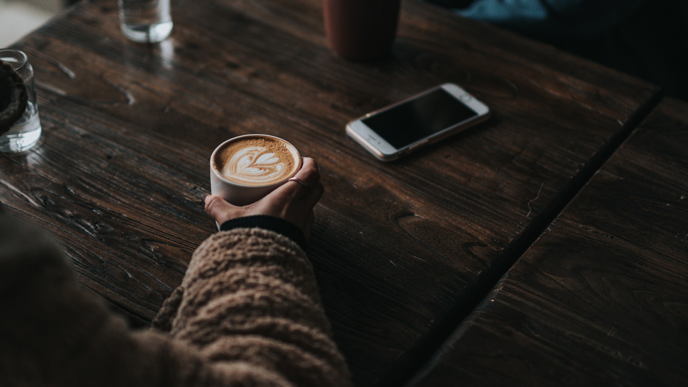 A latte on a wooden cafe table during a quiet conversation