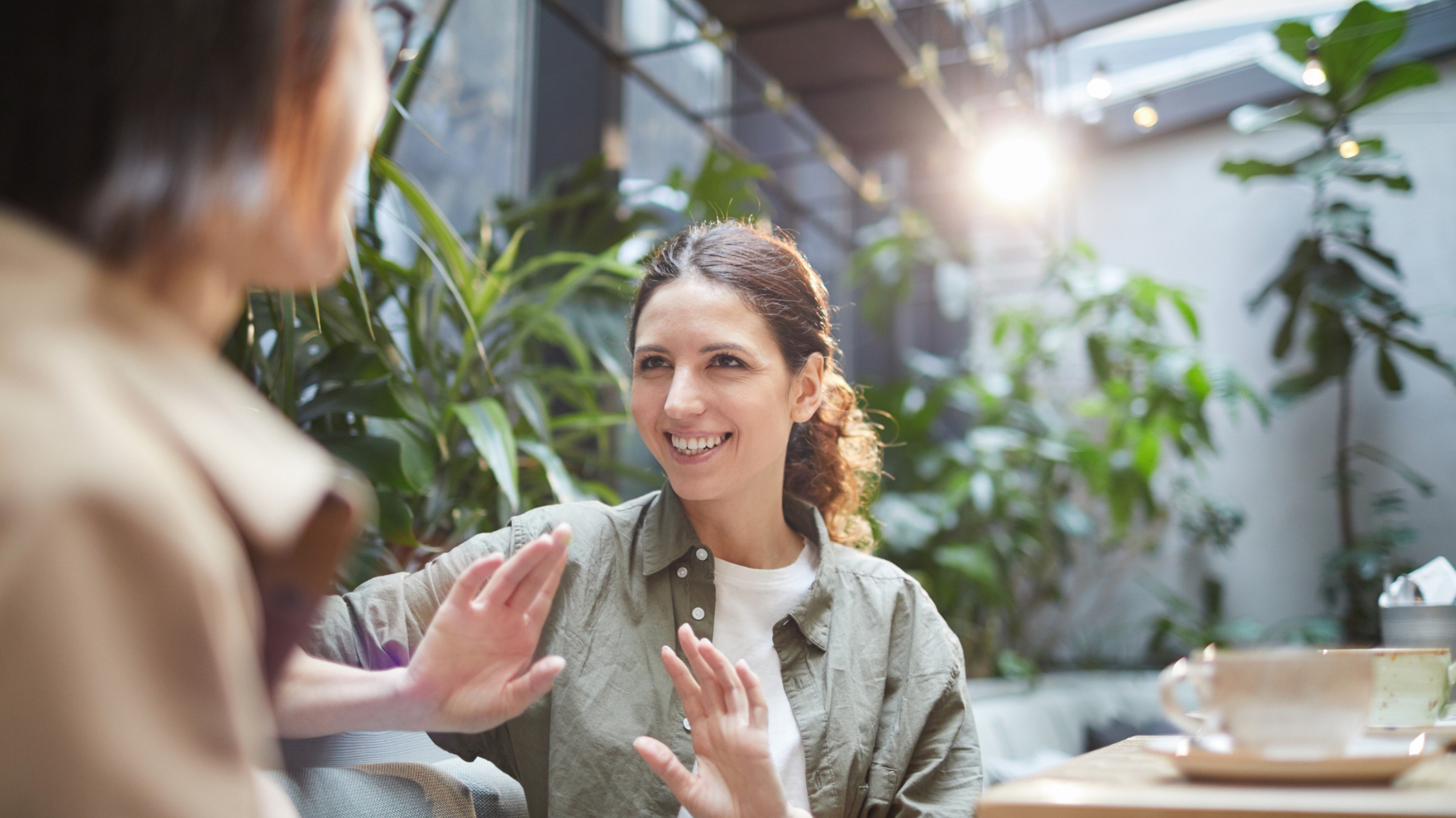 Two women talking over coffee in a bright cafe